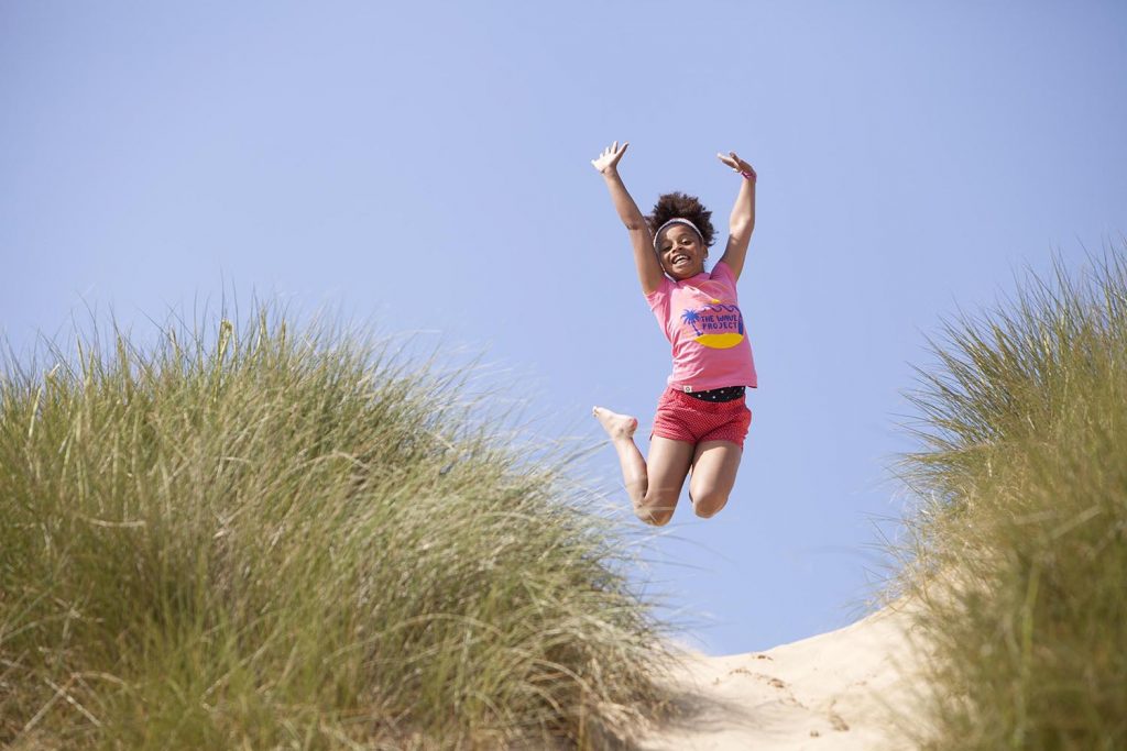 Child playing in the sand dunes on a Cornish beach