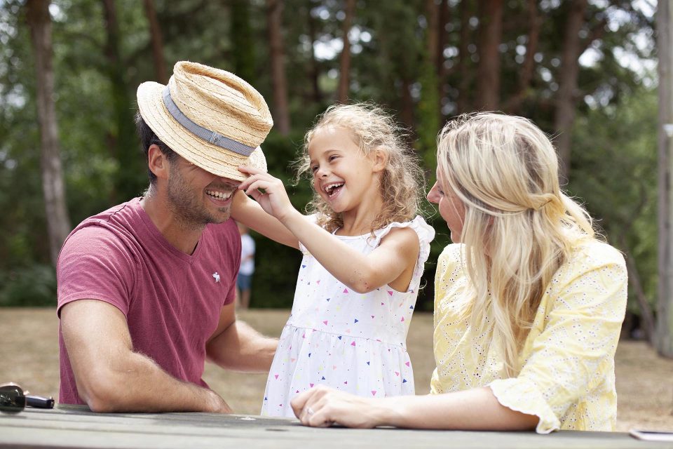 Daughter tilts dad's hat over his eyes as mum laughs