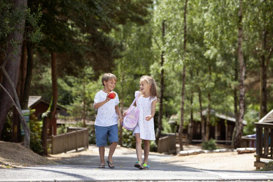 Brother and sister walk through the woodland holiday park