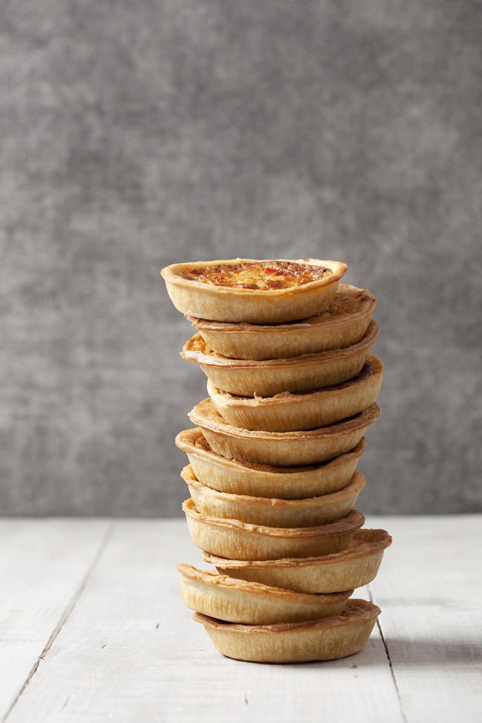 Photo of quiches piled high in a tower. Made by Crantock Bakery in Cornwall