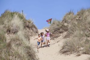Family fly kite on beach in Wales on campsite holiday.